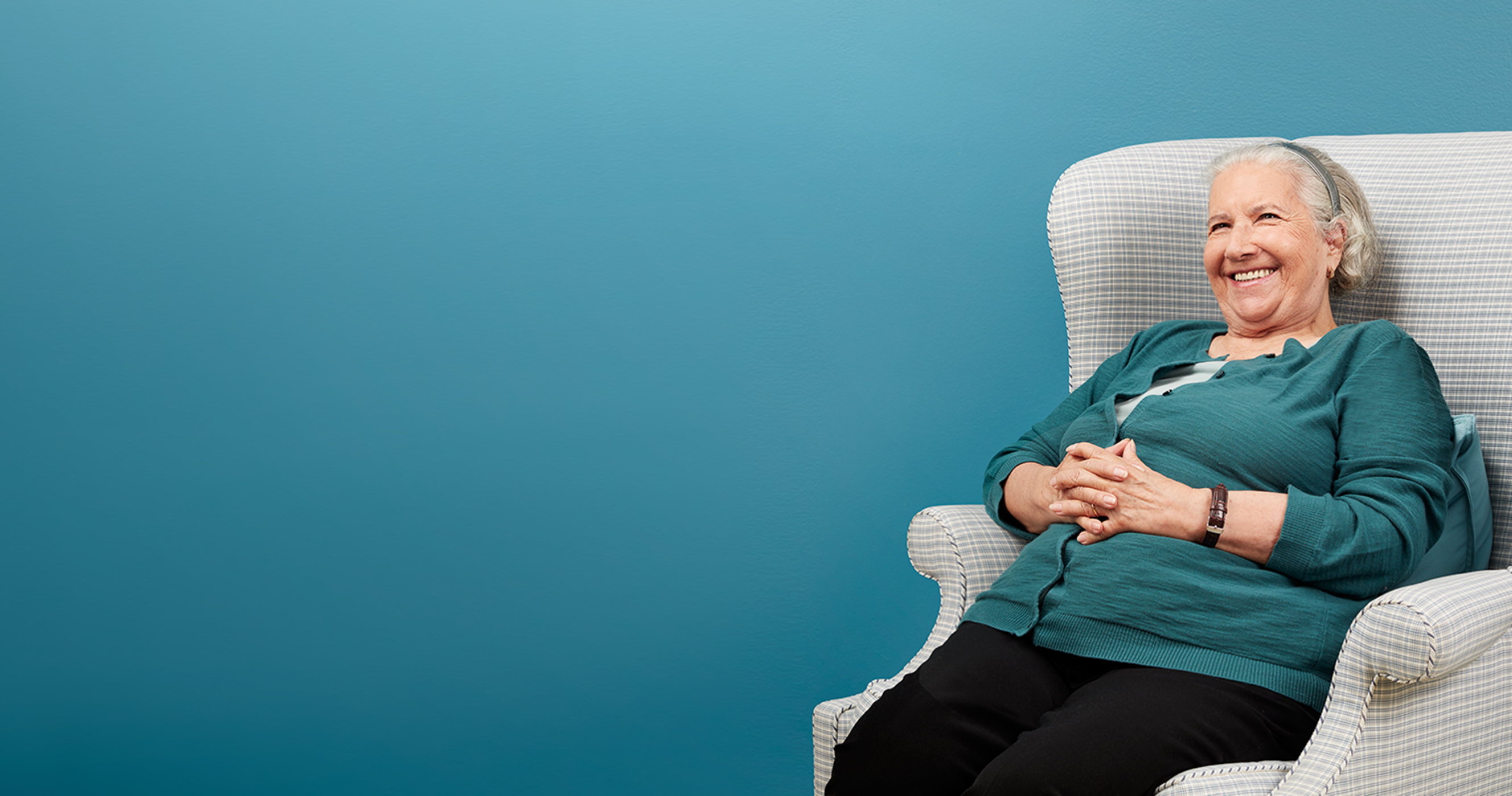 Member sitting in an arm chair smiling