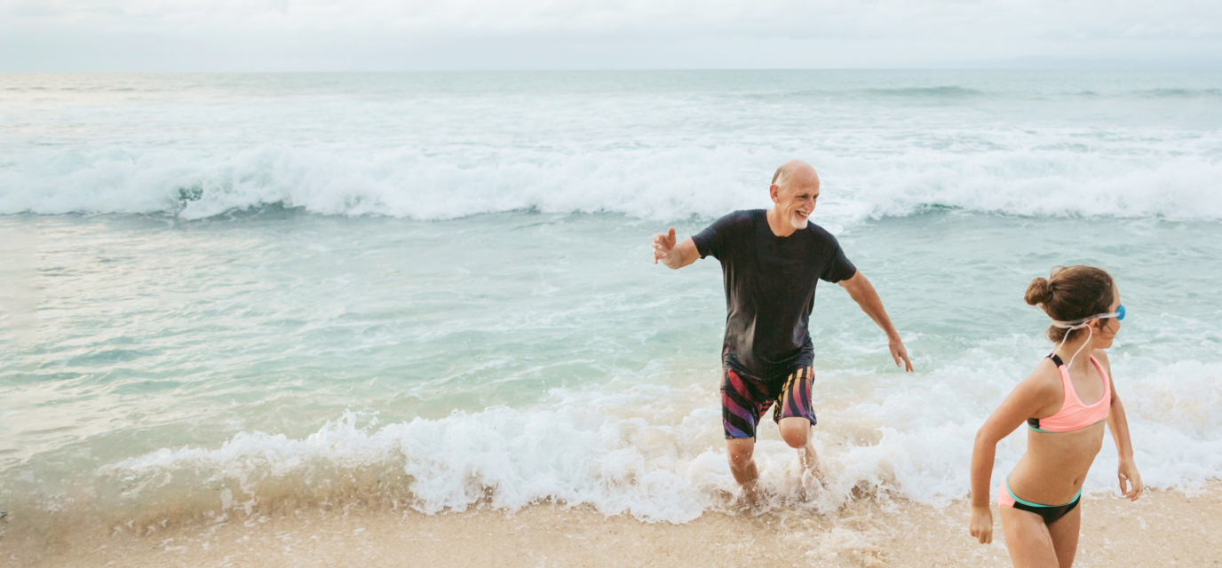 Grandfather and grandchild running on a beach