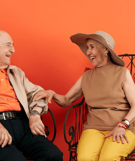 Clover Health members sitting laughing against an orange background